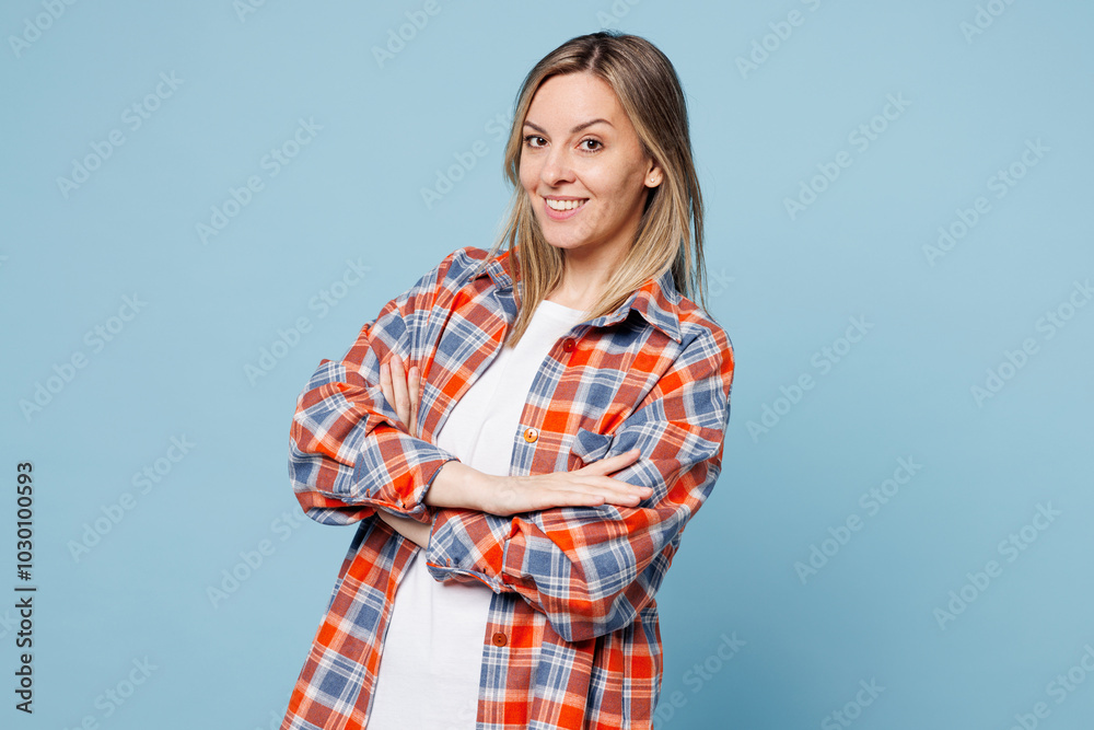 Φωτογραφία Side view young smiling happy woman wear red shirt t-shirt casual clothes hold hands crossed folded look camera isolated on plain pastel light blue cyan background studio portrait