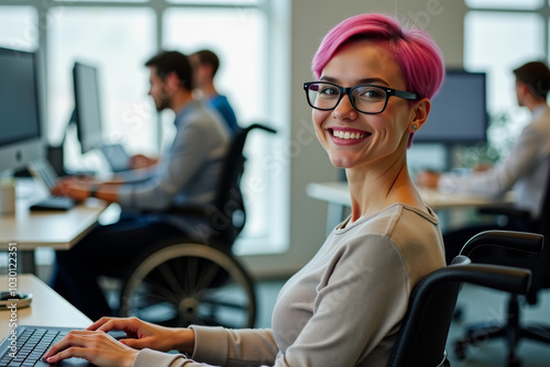 woman with pink hair in a wheelchair at work in the office against the background of colleagues