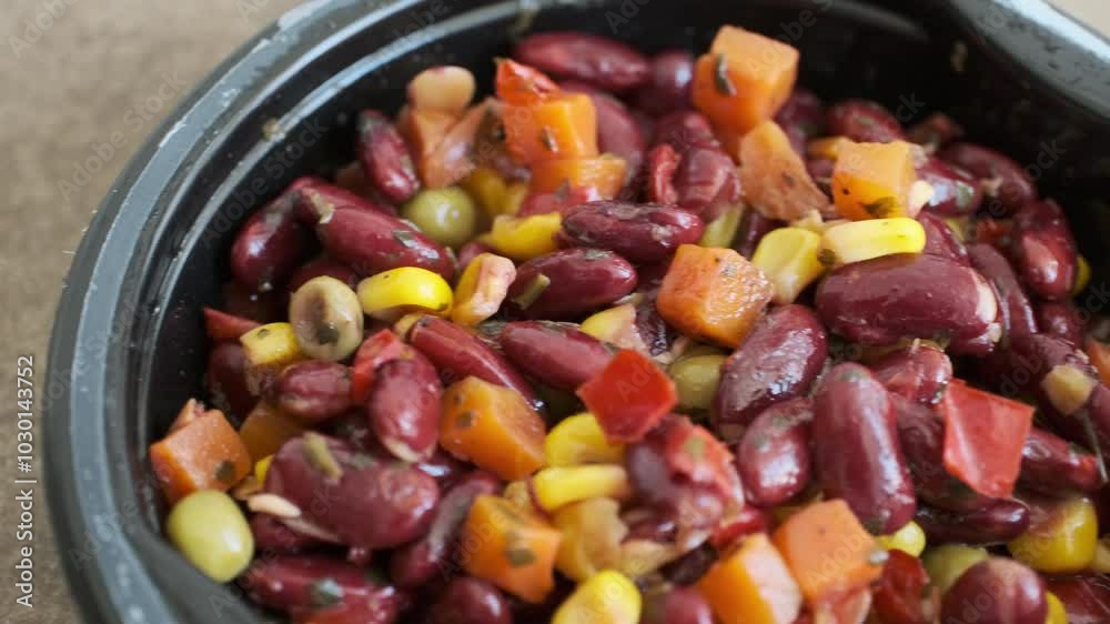 beans,corn,peas and carrots in black plastic bowl on brown background beans,corn,peas and carrots in black plastic bowl on brown background