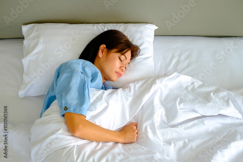Woman lying in bed on her side with a hand under the pillow