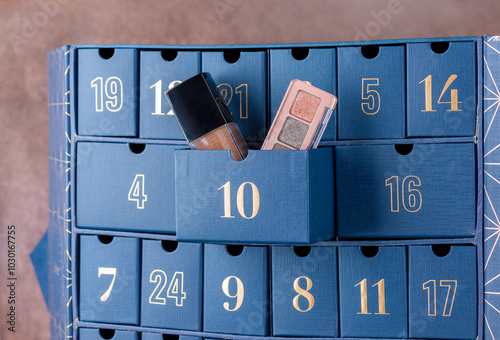 Advent calendar, blue boxes with numbers with decorative cosmetics for makeup gift, closeup. Waiting, Christmas countdown.