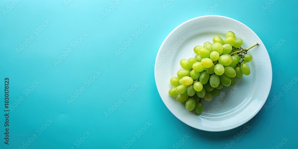 Minimalist white plate with green grapes on blue background Minimalist white plate with green grapes on blue background