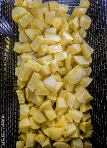 Basket of dices potatoes in the deep fryer photo