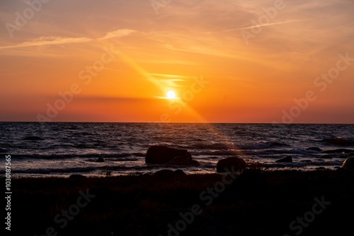 Sunset over the sea with silhouetted rocks.