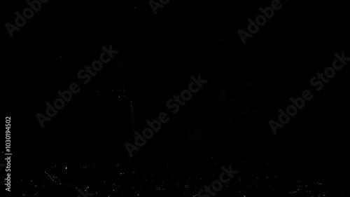 Aerial drone flight through night video of fireworks show. Dazzling intense colours glowing over the small town. Prepared for the New Year