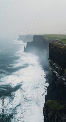 Misty cliffs along the rugged coastline with crashing waves and foggy atmosph...