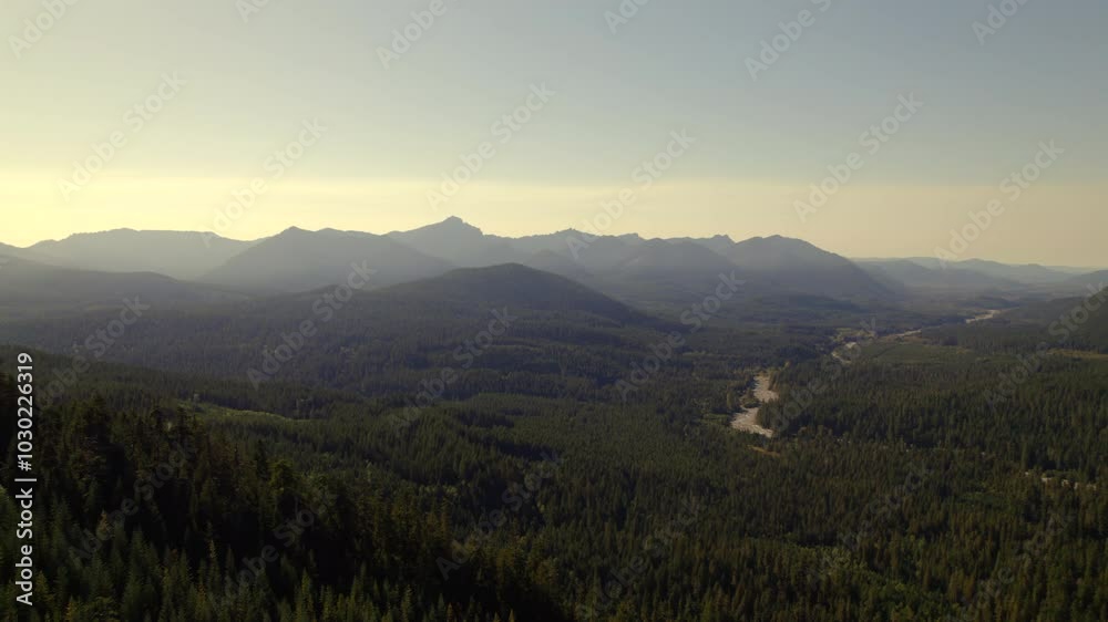 Aerial view of forested valley, Mount Rainier, and rugged mountain terrain in the Pacific Northwest at sunset. Aerial view of forested valley, Mount Rainier, and rugged mountain terrain in the Pacific Northwest at sunset.