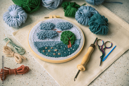 Side view of blue sea landscape embroidered in a hoop with punch needle, scissors and yarns of matching colors.