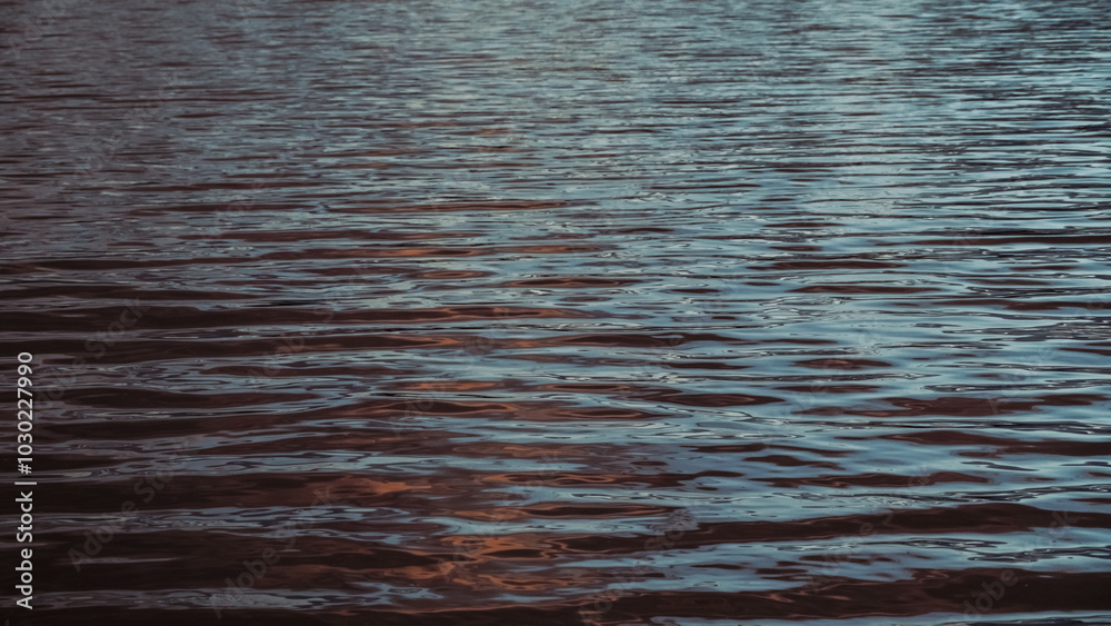 Sunlight plays on the calm sea waves. The surface of the sea water at sunset. Ripples on the water in close-up. Sunlight plays on the calm sea waves. The surface of the sea water at sunset. Ripples on the water in close-up.