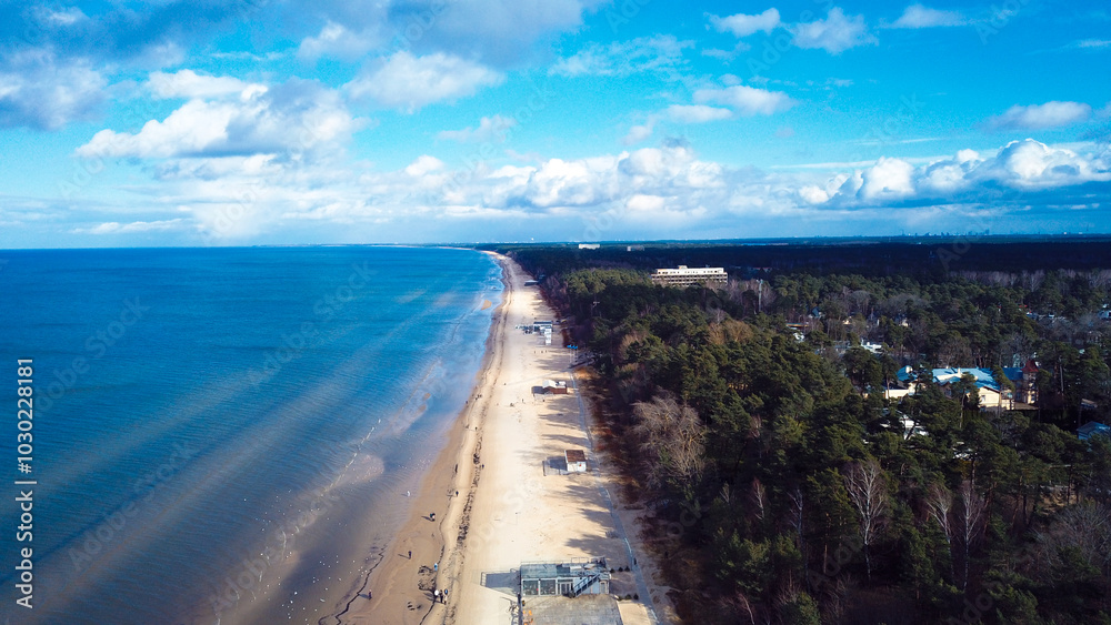 Fototapeta premium Breathtaking aerial view of Jurmala's coastline showcasing golden sands and lush greenery under a vibrant blue sky in late afternoon light
