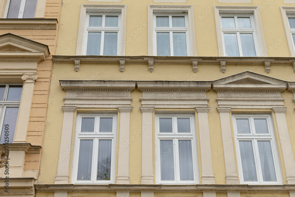 A bright yellow building that features numerous windows all over its facade, creating a vibrant and welcoming appearance A bright yellow building that features numerous windows all over its facade, creating a vibrant and welcoming appearance