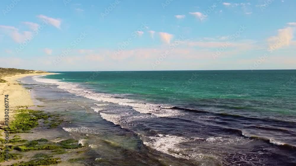 Waves gently roll onto a scenic shoreline on a bright sunny day with clear skies Waves gently roll onto a scenic shoreline on a bright sunny day with clear skies