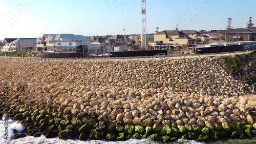 Rocky sea wall and waterfront homes at Claytons Residences in Mindarie, Australia on a sunny day photo