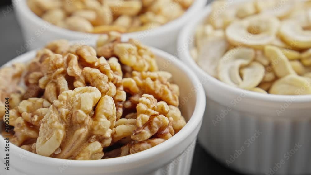 Different nuts in white bowls rotating. Cashew, peanuts, walnuts. Natural food background. Vegetarian food concept. Healthy lifestyle. Cinematic footage. Close-up in 4K, UHD Different nuts in white bowls rotating. Cashew, peanuts, walnuts. Natural food background. Vegetarian food concept. Healthy lifestyle. Cinematic footage. Close-up in 4K, UHD