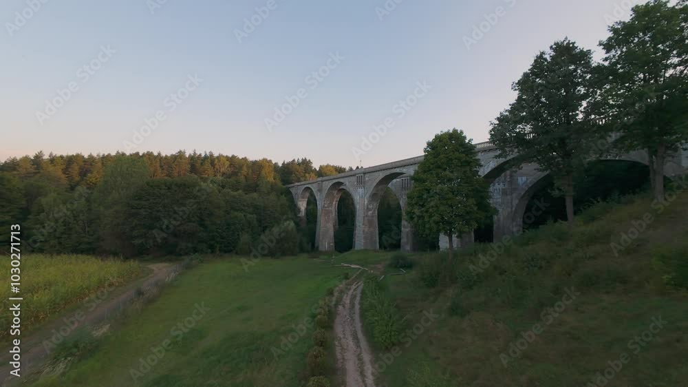 Aerial view of the historic Stanczyki Bridge amidst lush greenery and fields under the evening sky in Poland. High quality 4k footage Aerial view of the historic Stanczyki Bridge amidst lush greenery and fields under the evening sky in Poland. High quality 4k footage