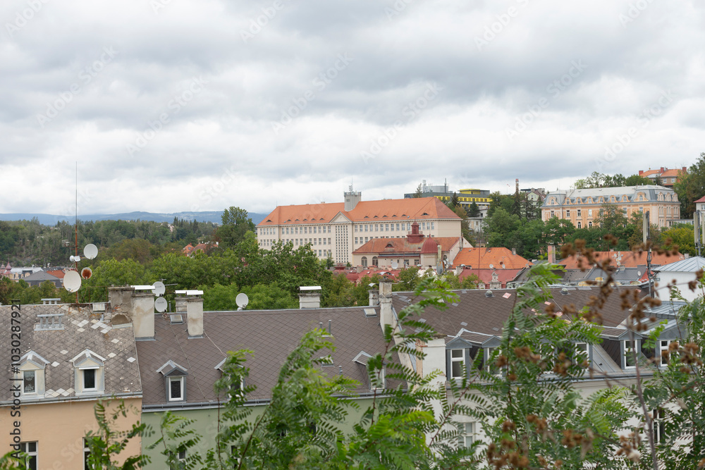 Obraz premium A bustling city filled with numerous tall buildings, complemented by verdant trees and lush greenery in the foreground, creating a vibrant urban landscape