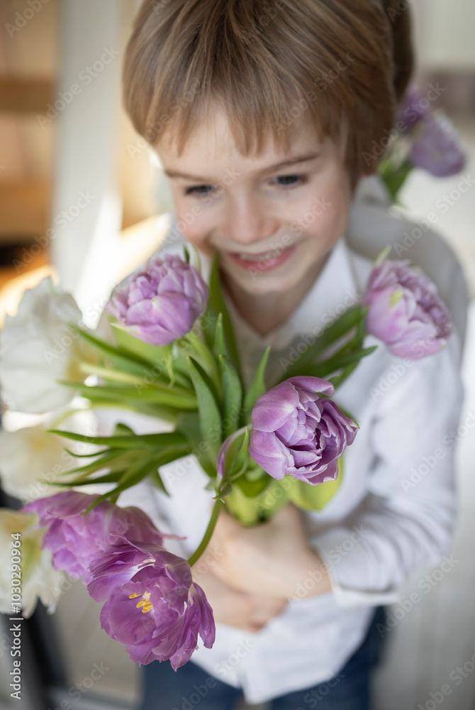 portrait of a happy boy out of focus. in the foreground there are beautiful lush tulip flowers. selective focus. Bouquet for congratulations on Valentine's Day, Mother's Day. Tenderness of childhood. portrait of a happy boy out of focus. in the foreground there are beautiful lush tulip flowers. selective focus. Bouquet for congratulations on Valentine's Day, Mother's Day. Tenderness of childhood.