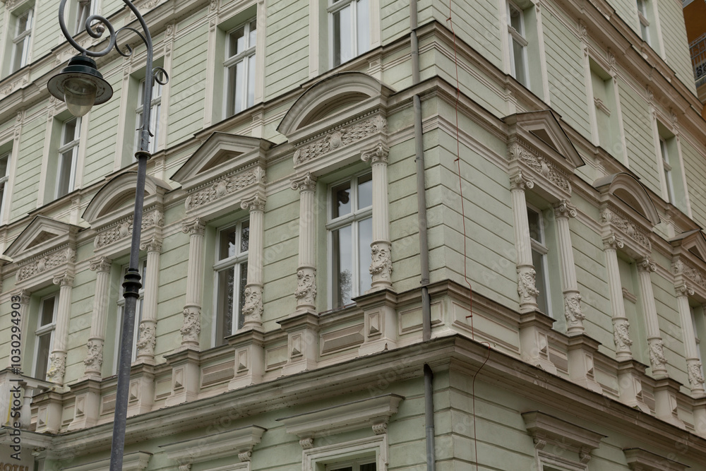 There is a large white building that features numerous windows as well as a street light positioned right at the corner of the structure There is a large white building that features numerous windows as well as a street light positioned right at the corner of the structure