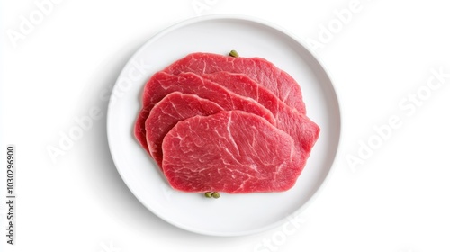 Fresh raw beef slices on white plate with green peppercorn garnish