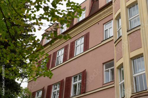 There is an attractive building that features numerous windows adorned with charming red shutters, enhancing its visual appeal and character