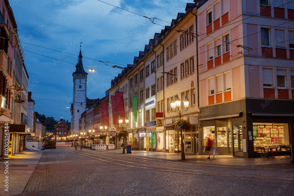 Naklejka premium Night street scene with a glowing houses and clock tower