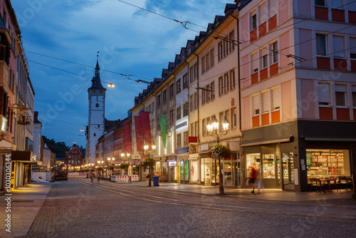 Night street scene with a glowing houses and clock tower