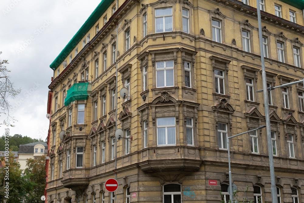 On the busy corner of a bustling street, there stands a large building adorned with a beautiful green roof that catches the eye On the busy corner of a bustling street, there stands a large building adorned with a beautiful green roof that catches the eye