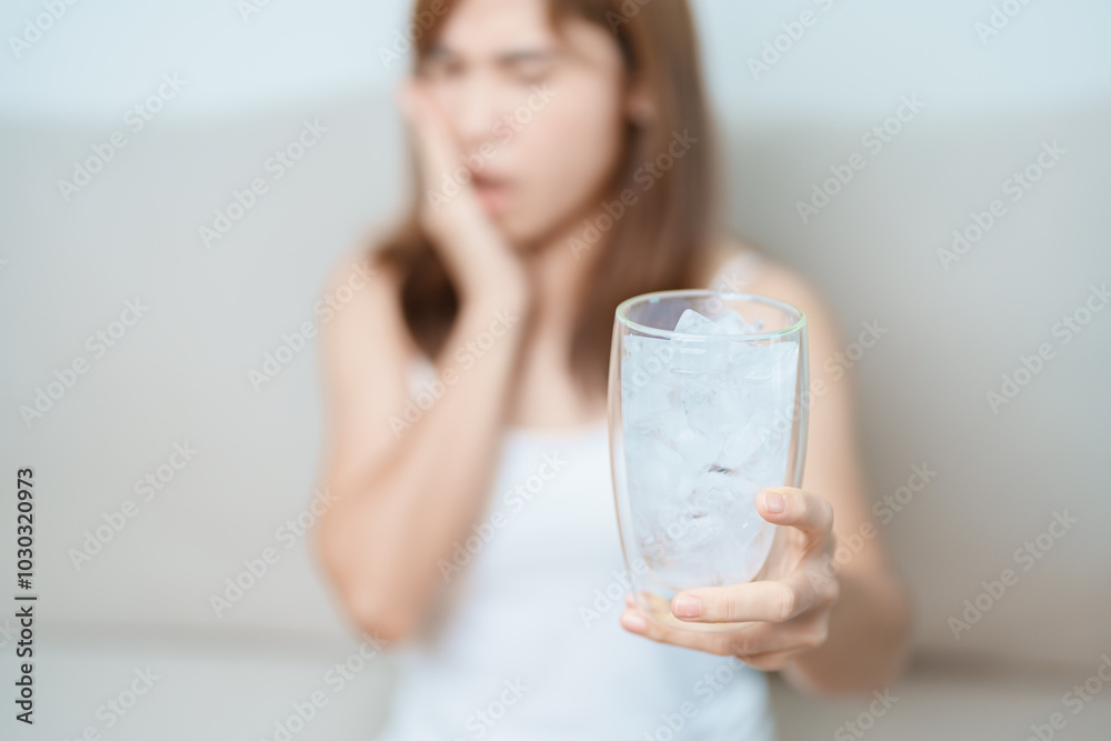 Teeth Sensitive to Cold concept. woman hold Ice Water glass and having toothache and pain after eat. Tooth Decay or Gum Disease, Grinding Teeth and Stress, Exposed Nerve Roots, Crack and Receding Gums Teeth Sensitive to Cold concept. woman hold Ice Water glass and having toothache and pain after eat. Tooth Decay or Gum Disease, Grinding Teeth and Stress, Exposed Nerve Roots, Crack and Receding Gums