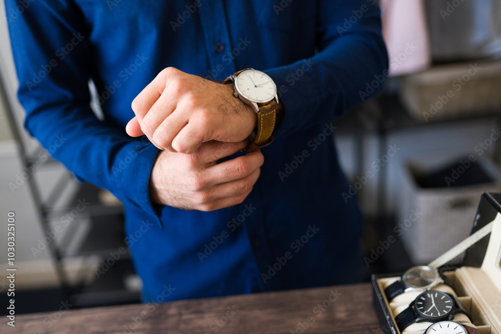 Sophisticated businessman making a fashion statement while adjusting wristwatch in walk-in closet filled with elegant clothes and accessories Sophisticated businessman making a fashion statement while adjusting wristwatch in walk-in closet filled with elegant clothes and accessories