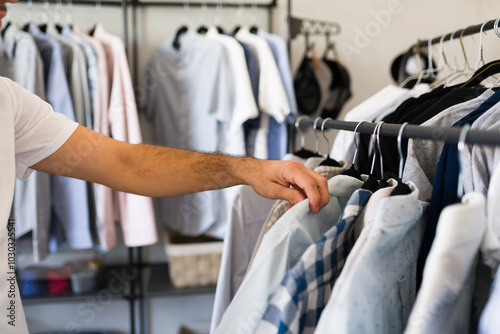 Closeup of a man choosing shirt in organized closet, reflecting personal style. Modern interior design adds efficiency to daily routine