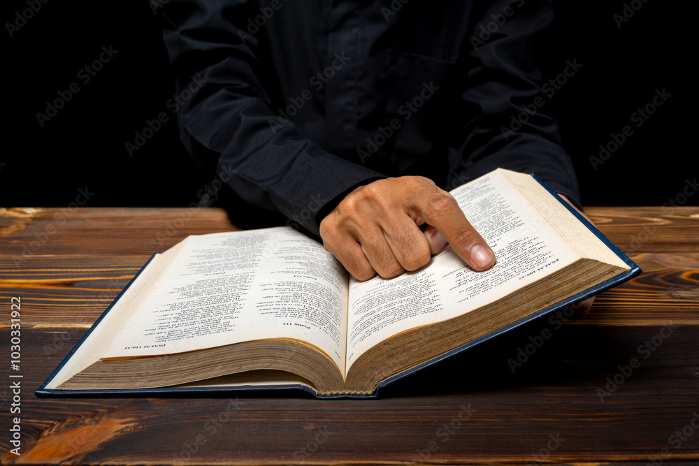 Fototapeta premium Man reading a holy bible in his hand. Symbol of faith and worship in God. People christianity prayer in church
