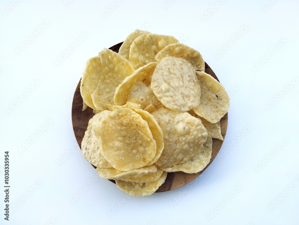 Opak or Cassava chips in wooden plate isolated on white background. Indonesian traditional foods Opak or Cassava chips in wooden plate isolated on white background. Indonesian traditional foods