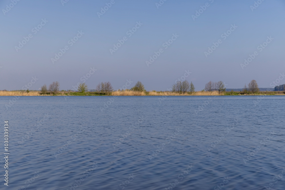 Naklejka premium The blue water in the lake reflects the blue sky in spring