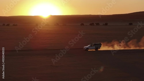 Aerial view of a 4x4 car driving on a gravel road in Namib desert in Sossusvlei National Park during a beautiful sunsets and vacations, Namibia, Africa