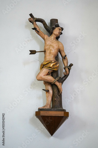 A wooden sculpture depicts Saint Sebastian tied to a tree and pierced with arrows