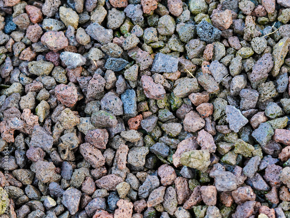 A collection of small, multicolored volcanic rocks is scattered across the ground A collection of small, multicolored volcanic rocks is scattered across the ground