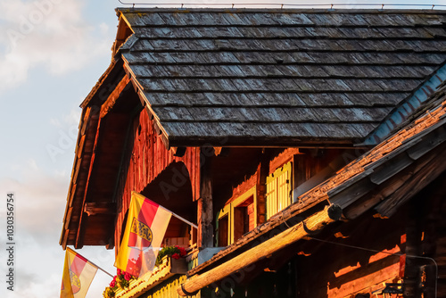 Traditional Austrian chalet in warm glow of setting sun on Lammersdorfer Alm, Milstatt, Carinthia, Austria. Wooden exterior adorned with Carinthian flag. Vacation and wanderlust vibes in Austrian Alps photo