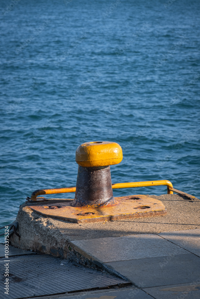 yellow rusty bollard on the quay. passenger ferry pier. sea in the background. yellow rusty bollard on the quay. passenger ferry pier. sea in the background.