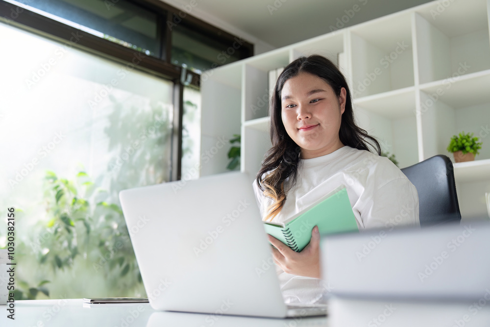 Young Fat Woman Learning and Planning with Notebook in Home Workspace Young Fat Woman Learning and Planning with Notebook in Home Workspace