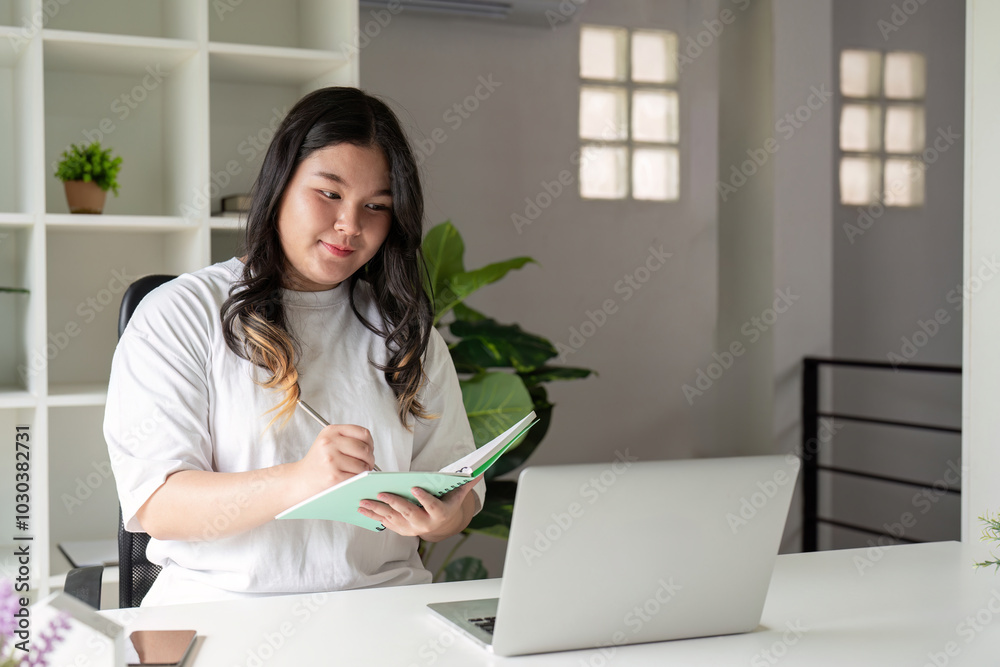 Focused Fat Woman Taking Notes from Laptop in Modern Home Office Focused Fat Woman Taking Notes from Laptop in Modern Home Office