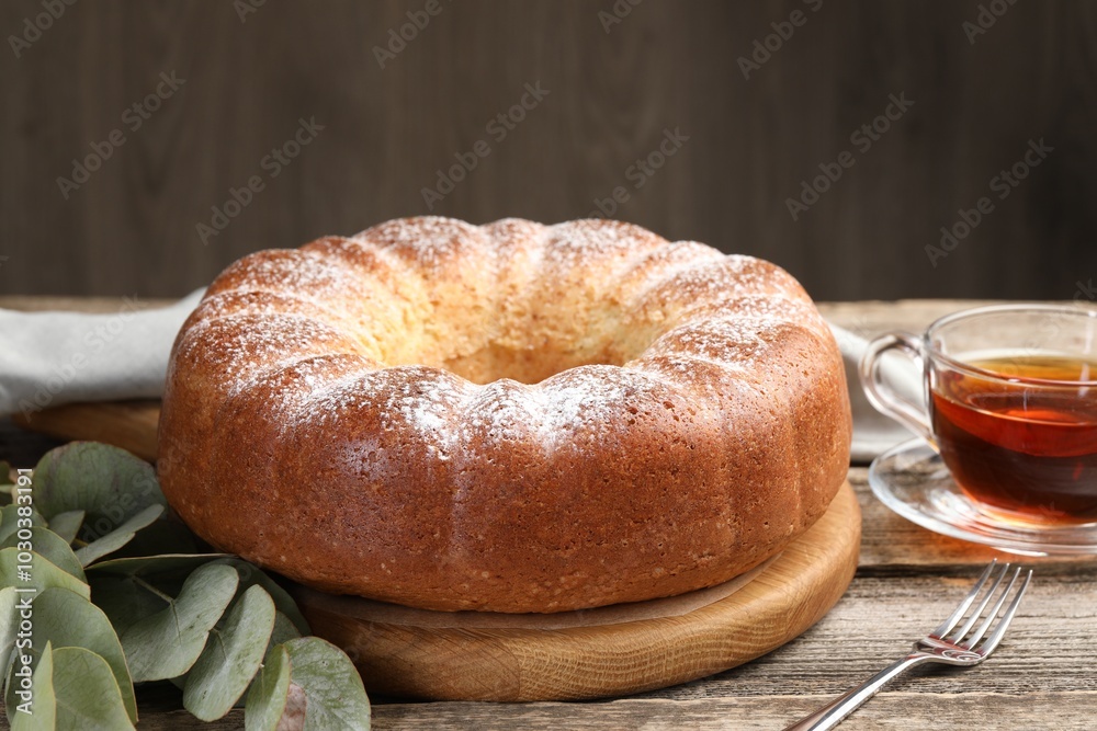 Freshly baked sponge cake, tea and eucalyptus leaves on wooden table, closeup Freshly baked sponge cake, tea and eucalyptus leaves on wooden table, closeup