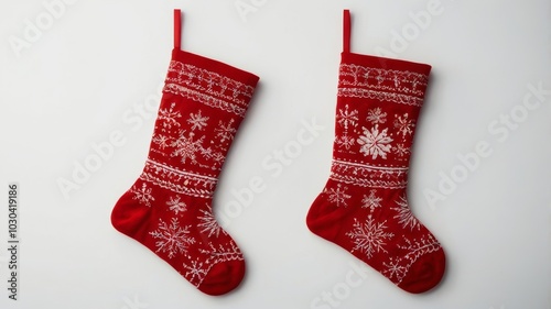 Two red christmas stockings with snowflakes hanging on white background