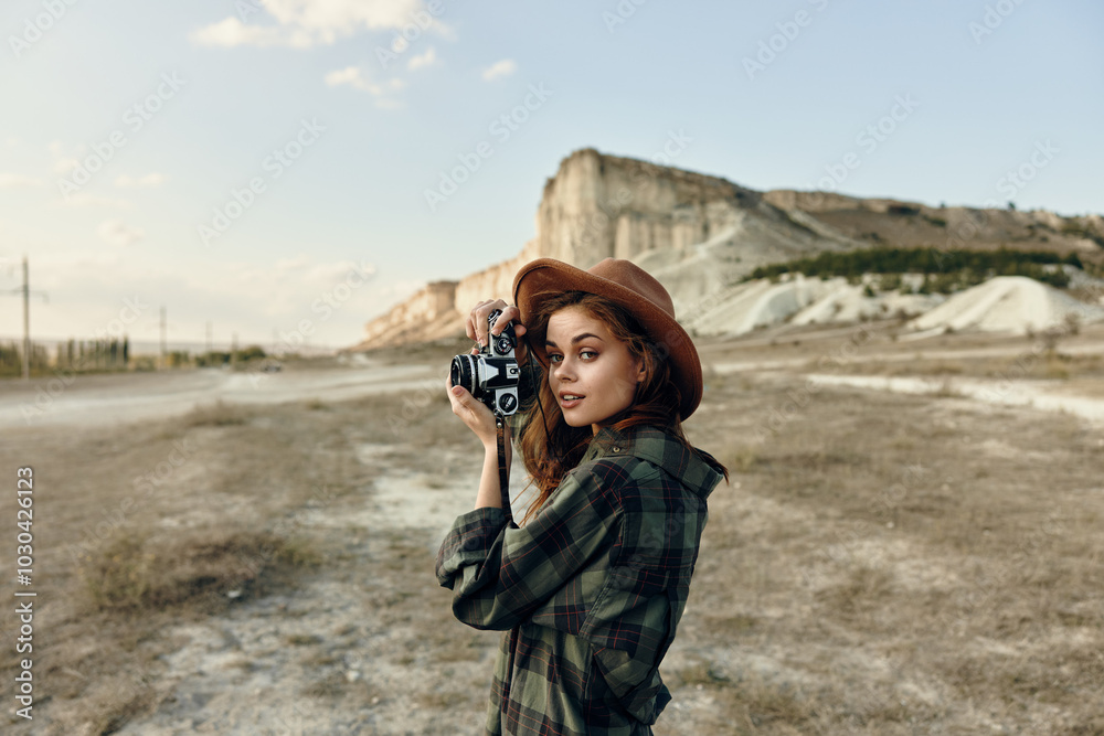 Obraz premium Woman in plaid shirt and hat capturing nature with vintage camera in scenic field