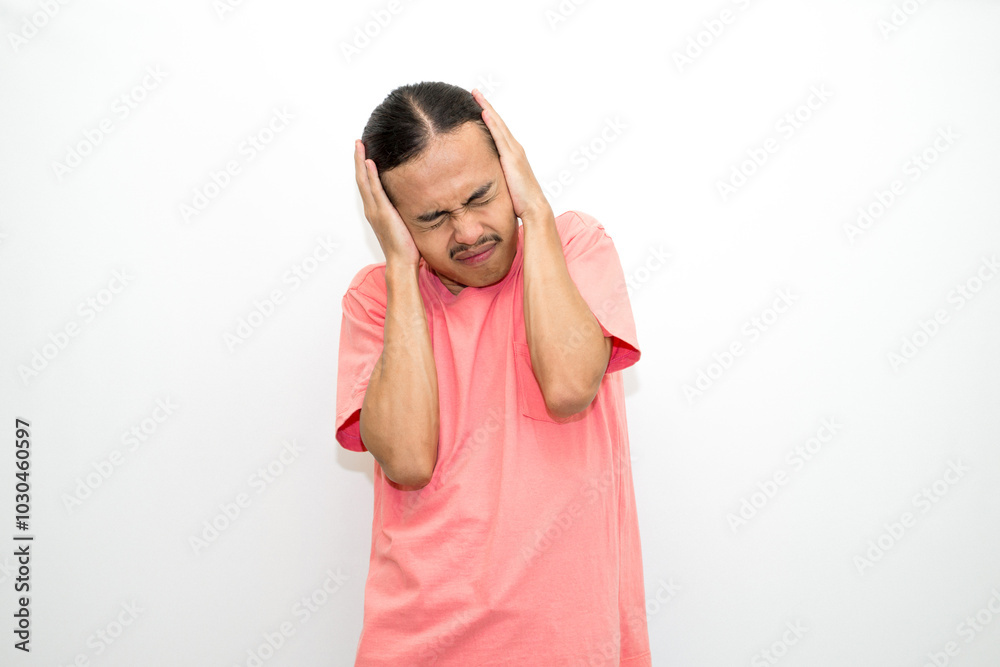 An Indonesian, Asian man wearing a pink tshirt having a headache, chest pain and stomach ache with hands holding head, chest and stomach. isolated in white background An Indonesian, Asian man wearing a pink tshirt having a headache, chest pain and stomach ache with hands holding head, chest and stomach. isolated in white background