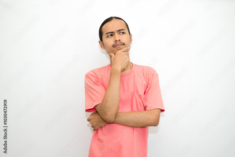 Asian, Indonesian man standing with his hand on his chin and head as if in deep thought, thinking about work or schoolwork. Isolated on white background Asian, Indonesian man standing with his hand on his chin and head as if in deep thought, thinking about work or schoolwork. Isolated on white background