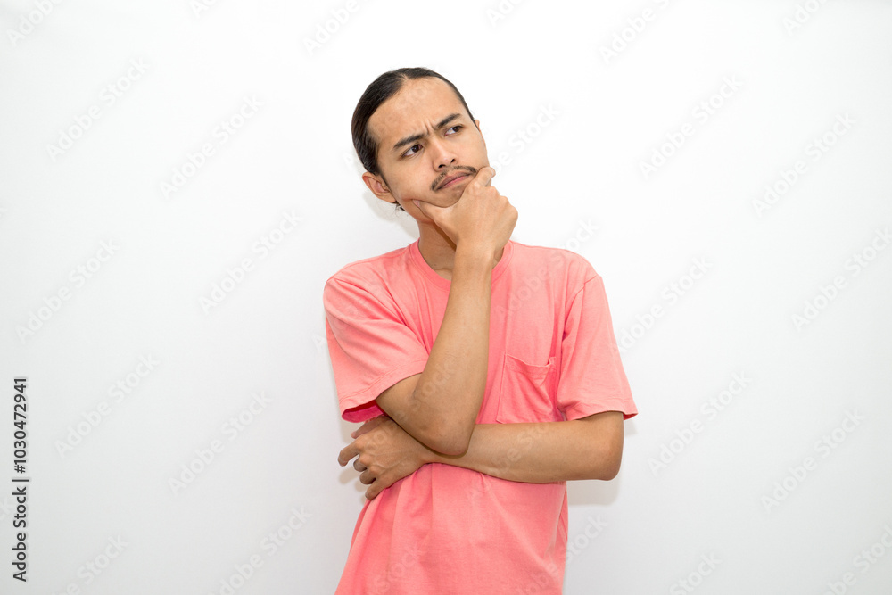 Asian, Indonesian man standing with his hand on his chin and head as if in deep thought, thinking about work or schoolwork. Isolated on white background
