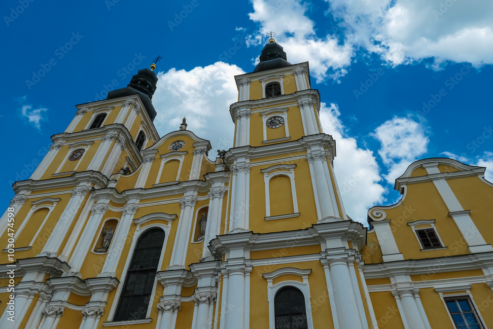 Obraz premium Low angle view of majestic church Basilika Mariastrost with two magnificent bell towers in Graz, Styria, Austria, Europe. Sky filled with fluffy white clouds; heaven atmosphere on religious site.