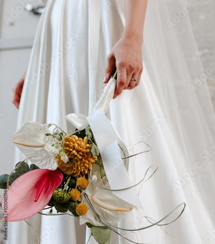 Obraz na płótnie Elegant bridal bouquet with tropical flowers and modern ribbon details held by a bride in a wedding dress. w salonie