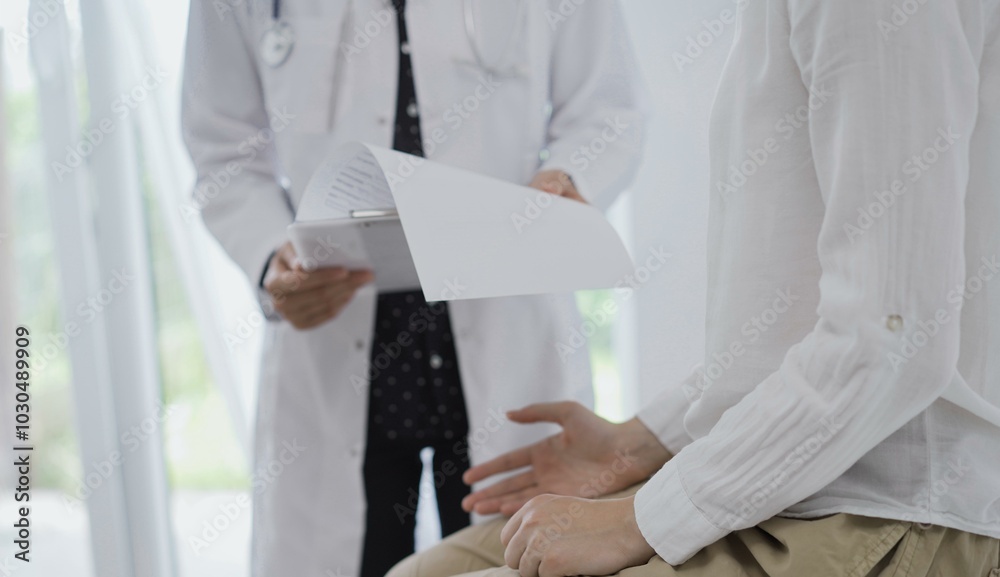 Doctor and a patient. The female physician, wearing a white medical coat standing with a clipboard during a consultation in the clinic, close up of patient's hands. Medicine concept Doctor and a patient. The female physician, wearing a white medical coat standing with a clipboard during a consultation in the clinic, close up of patient's hands. Medicine concept