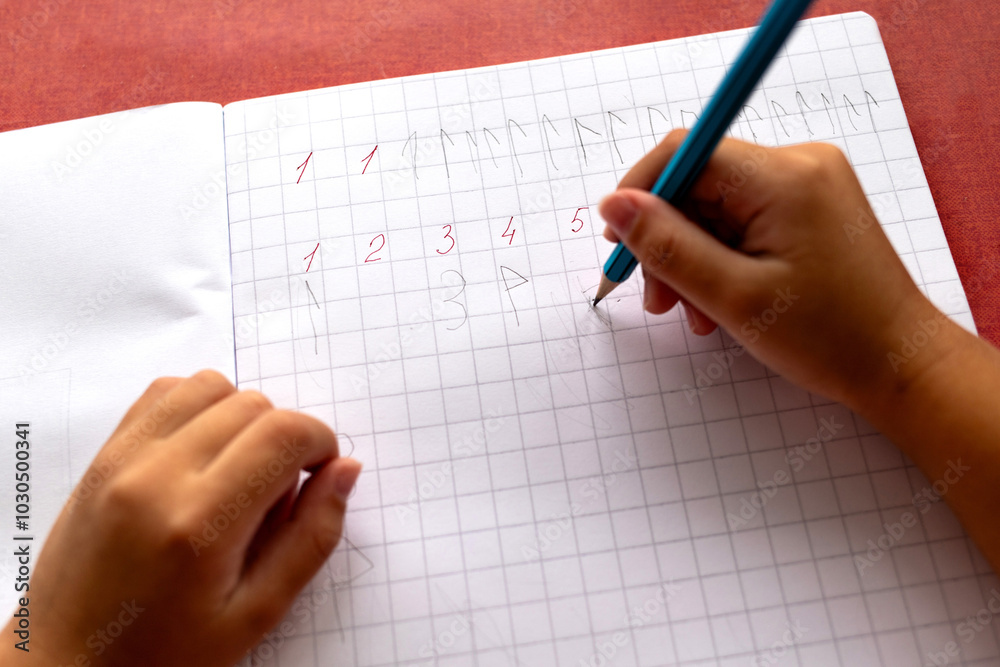 Child's hands writing numbers in a notebook. The problem of dysgraphia and dyscalculia. Child's hands writing numbers in a notebook. The problem of dysgraphia and dyscalculia.